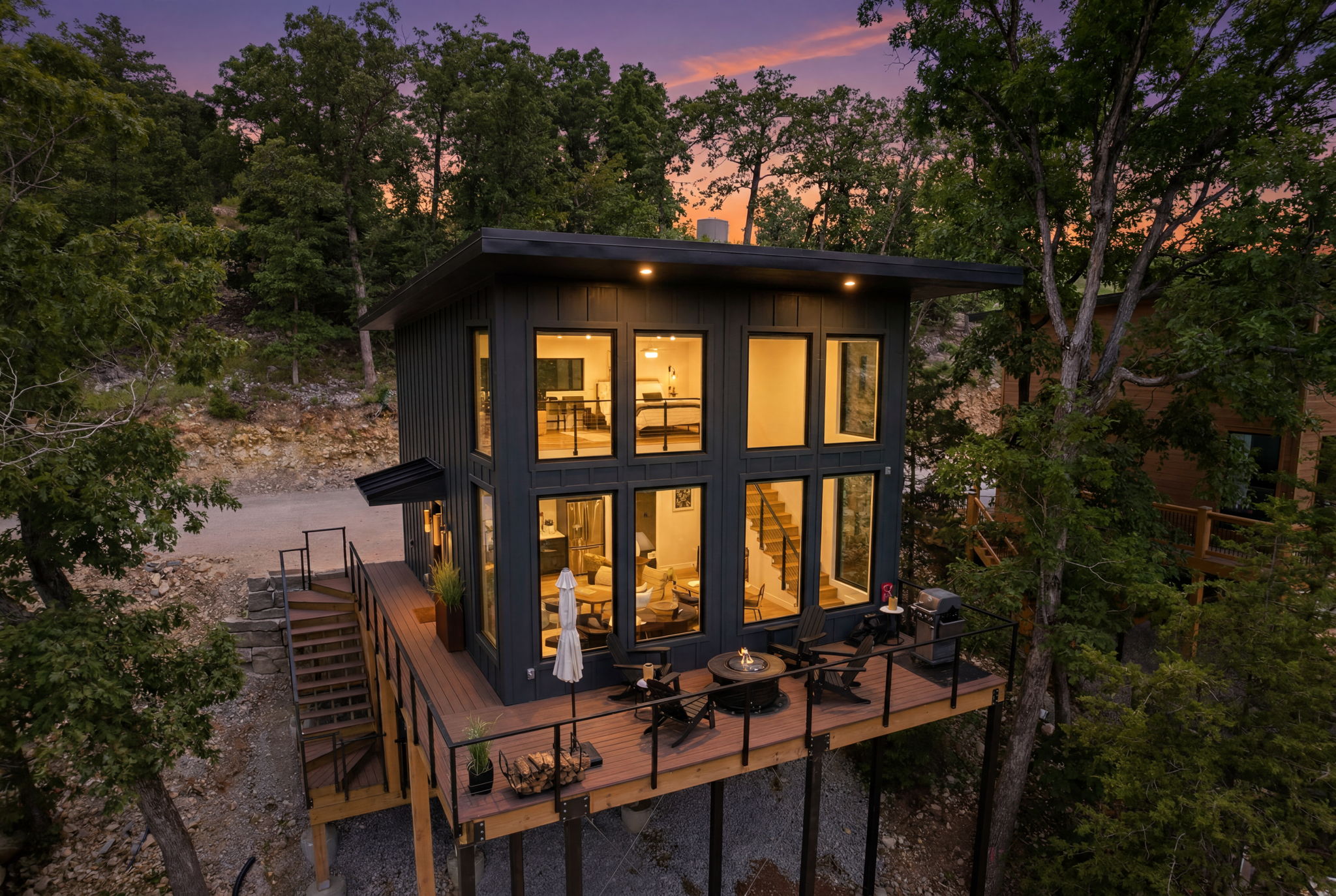 Aerial twilight view of a premium short-term rental glowing among the trees